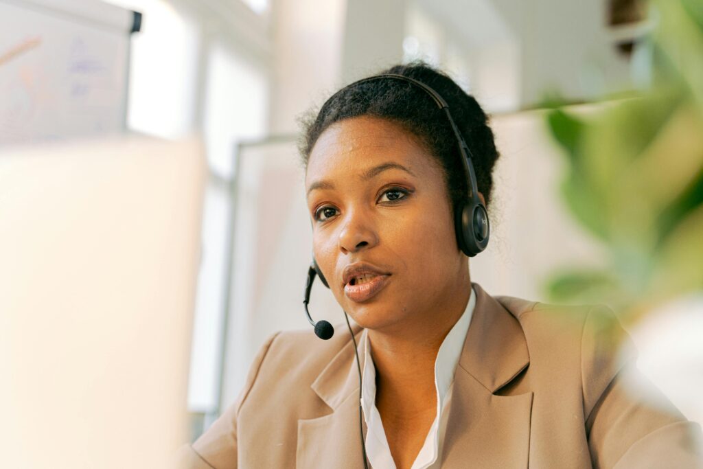 Building Efficient Support Teams Without Hiring In-House 2 A female customer support agent wearing a headset is focused on a computer screen in an office setting.