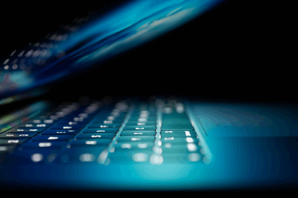 Creating a Secure Environment for Online Businesses: A How-to Guide  1 A close-up of a laptop keyboard illuminated by a bright, blue light in a dark room.
