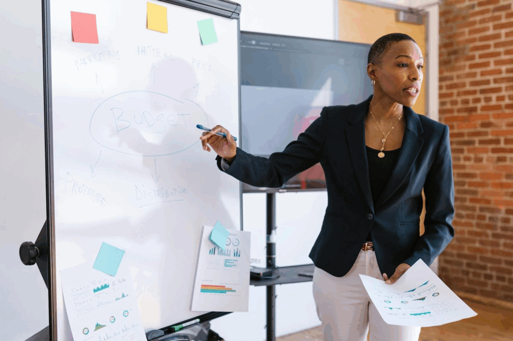 A Guide to Diagrams That Help You Tell a Business Story 1 A businesswoman in a blazer explaining a budget flowchart on a whiteboard to her colleagues.