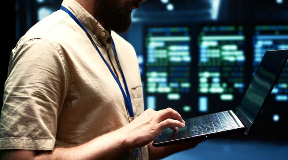 Why Network Device Configuration Backups Matter for IT Operations 1 An IT specialist holding a laptop while managing server configurations inside a high-tech data center.